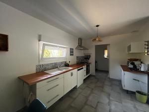 a kitchen with white cabinets and a sink and a window at Entre Lac et Océan in Hourtin