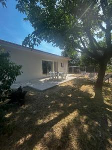 a backyard with a table and chairs and a tree at Entre Lac et Océan in Hourtin
