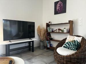 a living room with a flat screen tv and a chair at Entre Lac et Océan in Hourtin