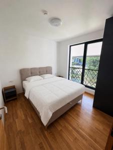 a white bedroom with a large bed and a large window at Treska Kop Luccas Residence in Cajetina