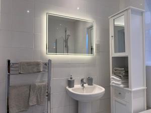 a white bathroom with a sink and a mirror at The Hideaway - Secluded Studio Annexe in Cambourne