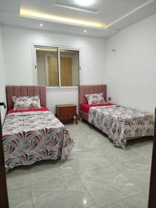 a room with two beds and a window at Maison lemjid in Kelibia