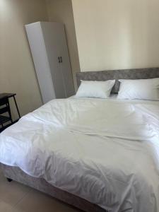 a large white bed with white sheets and pillows at City centre Apartment in Kigali