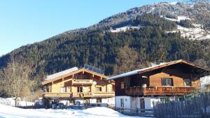 a couple of buildings in the snow with a mountain at Appartements Berger Kitzbühel in Kitzbühel