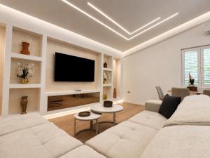 a living room with a white couch and a flat screen tv at Vila Kordhaku in Petrelë