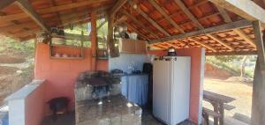a small kitchen with a refrigerator and a table at Chalé Estalagem Vô Jasôn in Itamonte