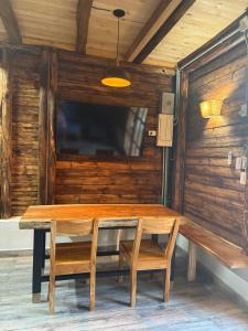 a wooden table with a bench and a tv on a wall at Cabaña Vivanco in Coveñitas