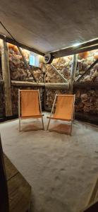 two chairs sitting in a room with a stone wall at Kierunek Puszcza 2 Apartamenty - Balia, Sauna, Grota solna - max 14 osob in Narewka