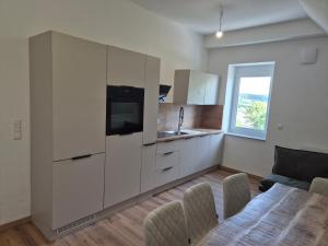 a kitchen with white cabinets and a table with chairs at Ferienwohnung KEMS in Gundelsheim