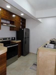 eine Küche mit einem schwarzen Kühlschrank und einer Spüle in der Unterkunft Casa Las Brisas in Progreso + 7 Fotos