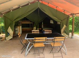 a tent with a table and chairs in it at Bungalow Kotaventure in Le Mesnil-Villement