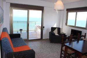 a living room with a table and chairs and a balcony at Apartamentos Guillem in Playa de Miramar