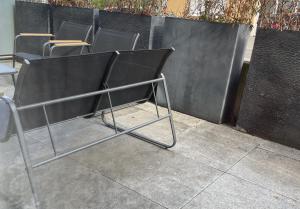 a metal chair sitting on a sidewalk next to a fence at studio siesta in Pétange