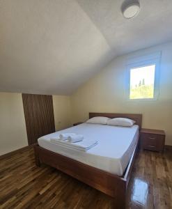 a bedroom with a bed with white sheets and a window at MontSky Apartment - Podgorica Airport in Mitrovići