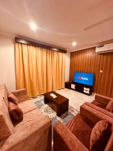 a living room with two couches and a flat screen tv at Britstar Suites Salalah in Salalah