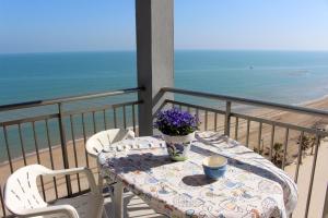 a table with flowers on a balcony with the beach at Apartamentos Guillem in Playa de Miramar
