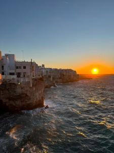 a sunset over the ocean next to a cliff at Benedamò Home Inside in Polignano a Mare