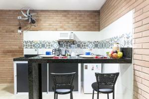 a kitchen with a counter with chairs in it at Kitnet Tijolo Ecológico 02 in Tamandaré