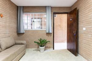 a living room with a couch and a window at Kitnet Tijolo Ecológico 02 in Tamandaré