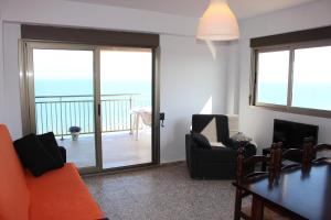 a living room with a couch and chairs and a balcony at Apartamentos Guillem in Playa de Miramar