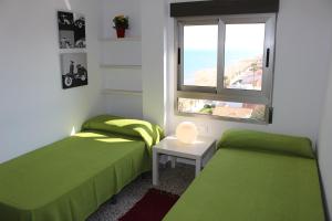 a bedroom with two green beds and a window at Apartamentos Guillem in Playa de Miramar