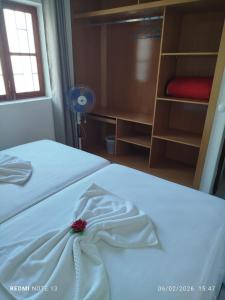 a bedroom with a white bed with a bow on it at Kasa Tabuga in Porto Novo +10 photos
