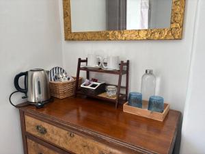 a wooden dresser with a coffee maker and a mirror at Birch Tree House in Windermere