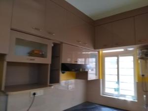 a kitchen with brown cabinets and a window at North Grande in kolkata +3 photos