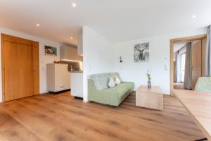 a living room with a green couch and a kitchen at Hotel Hertehof in Damuls