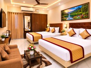 a hotel room with two beds and a couch at Saravana Residency in Allinagaram