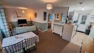 a living room with two baby cribs and a kitchen at Oak Bungalow in Carbis Bay