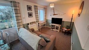 a living room with a couch and a television at Oak Bungalow in Carbis Bay