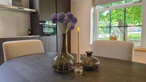 a vase with purple flowers sitting on a table at Vakantiewoning In de boerderij in Arum