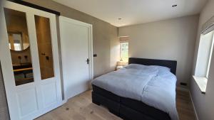 a bedroom with a bed and a door to a bathroom at Vakantiewoning In de boerderij in Arum