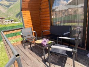 a porch with two chairs and a table and a television at Tobani Cottage Kazbegi in Kazbegi