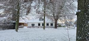 a house in a yard covered in snow at Vakantiewoning In de boerderij in Arum +8 photos
