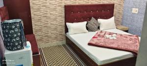 a small room with a bed and a chair at Qasmi Hotel in Jammu +4 photos
