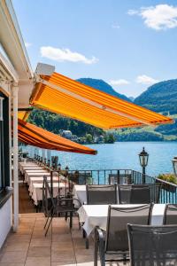 a patio with tables and chairs and a view of the water at Seehotel Schwert in Gersau