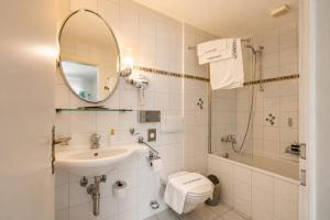 a bathroom with a sink and a toilet and a mirror at Seehotel Schwert in Gersau +42 photos