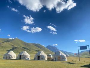 a group of tents in a field with mountains at Kel-Suu Manap in Kol-Suu