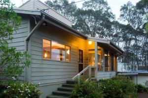 a small white house with a porch and stairs at Seascapes at Rosedale in Tomakin
