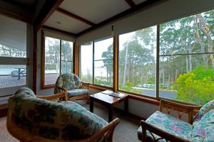 a living room with chairs and a table and windows at Seascapes at Rosedale in Tomakin