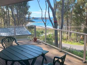 a deck with a table and chairs and a view of the ocean at Seascapes at Rosedale in Tomakin