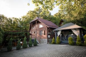 a wooden house with a pavilion next to a driveway at Cabana Toth Mic&Mare in Sovata