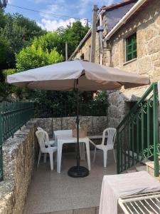 a table and chairs under an umbrella on a patio at Refúgio Rural no Gerês - Casa Araujo de Sousa in Terras de Bouro