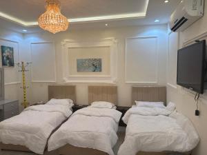 a room with four beds and a flat screen tv at غرفة نوم 3 أسرّة مدخل خاص بدون صالة in Al Baha