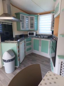 a small kitchen with green cabinets and a microwave at Camping La Tentation in Renty