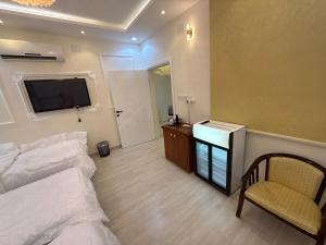 a bedroom with a bed and a tv and a chair at غرفة نوم 3 أسرّة مدخل خاص بدون صالة in Al Baha