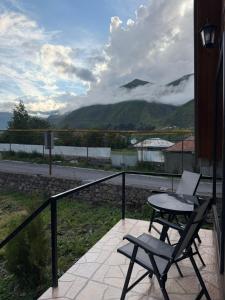 a table and a chair on a balcony with a view at Twenty 23 Cottages,kazbegi 1 in Kazbegi
