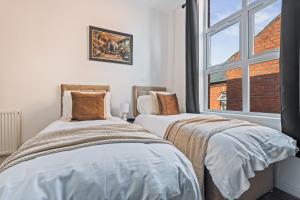 two beds in a room with a window at The Churchill Hotel in Coventry